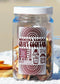 A clear glass jar filled with dried fruit slices and topped with a white lid, featuring a large brown and white label that reads 'Hermosa Sangria Craft Cocktail' and 'HB Craft Co.' The jar is photographed against a blurred beige background.