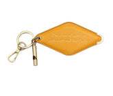 A mustard yellow diamond-shaped leather keychain with a brass key ring, split ring, and whistle. Engraved on the keychain is the phrase "I'm a ray of sunshine with scattered hot flashes."