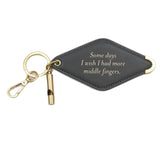 A balck diamond-shaped leather keychain with a brass key ring, split ring, and whistle. Engraved on the keychain is the phrase "Some days I wish I had more middle fingers."