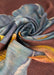 Close up of a wool scarf in dark purple, blue and golden green colors.