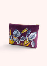 A deep grape purple colored velvet zip pouch, with blue iris flowers embroidered onto it, against a white background.