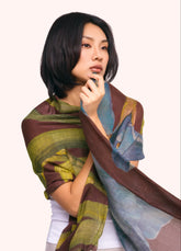 A woman with short black hair wearing a wool wrap scarf with a dark purple, blue and green floral pattern on it.