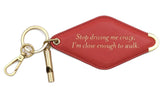 A red diamond-shaped leather keychain with a brass key ring, split ring, and whistle. Engraved on the keychain is the phrase "Stop driving me crazy, I'm close enough to walk."