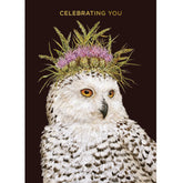 A black card with a painting of a snow owl with thistle flowers on its head for a crown. Gold text above it reads "Celebrating you".