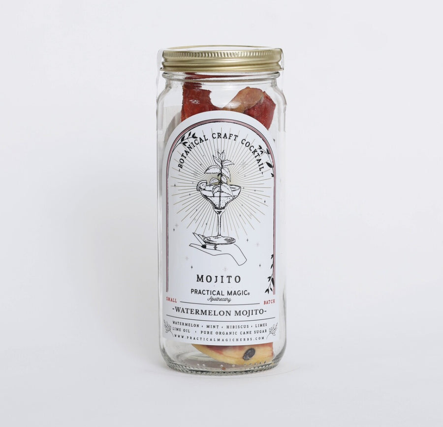 A clear glass jar with a gold metal screw-on lid, containing dried fruit pieces, with a white label reading 'Botanical Craft Cocktails Watermelon Mojito'. The jar is photographed against a white background.