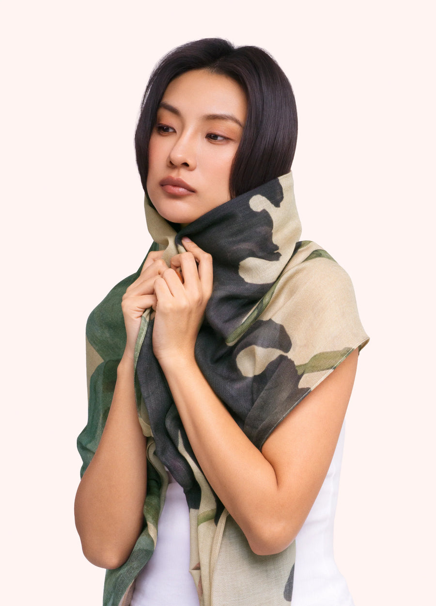 A woman with short black hair wearing a wool wrap scarf with a beige, dark purple and green floral pattern on it.